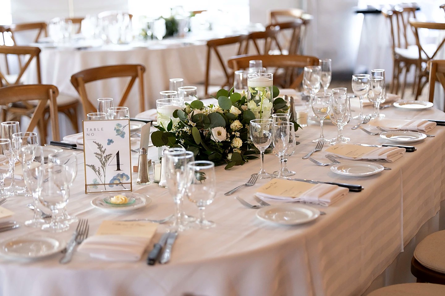 Reception table setting with a eucalyptus and white rose centerpiece